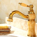 Luxury brass and jade basin faucet with gold finish, featuring a single-handle control, elegant design on a marble countertop.