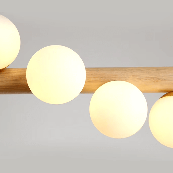 Modern minimalist strip chandelier with wooden beam and glowing orbs, perfect for dining tables or kitchen islands.