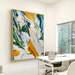 Vibrant abstract canvas art with yellow, blue, and green strokes in a modern office space.