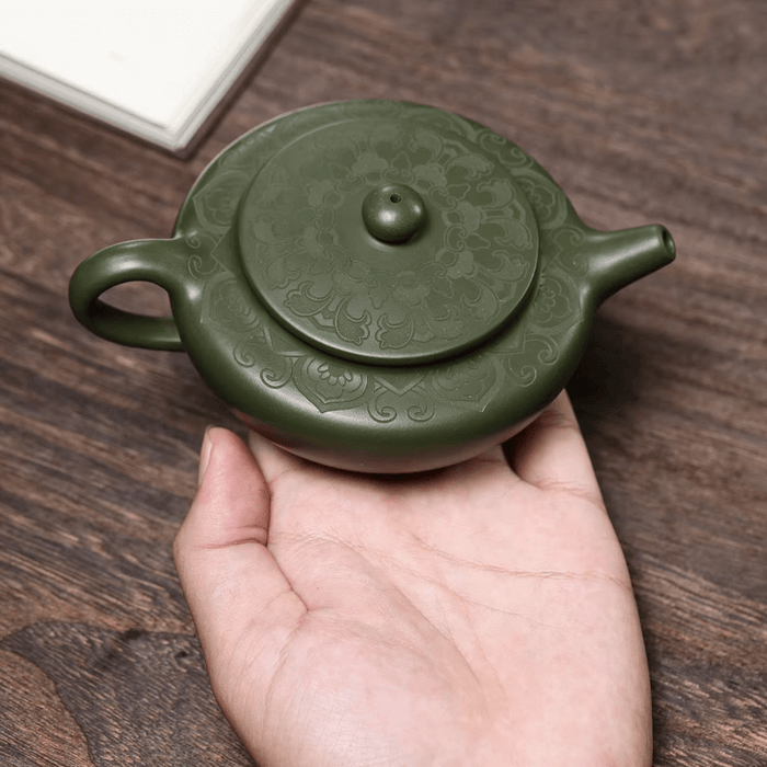 Handmade Green Yixing Clay Teapot in hand, showcasing intricate design and traditional craftsmanship.