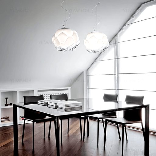 Modern dining area with two cloud glass chandeliers illuminating a sleek black table and chairs.