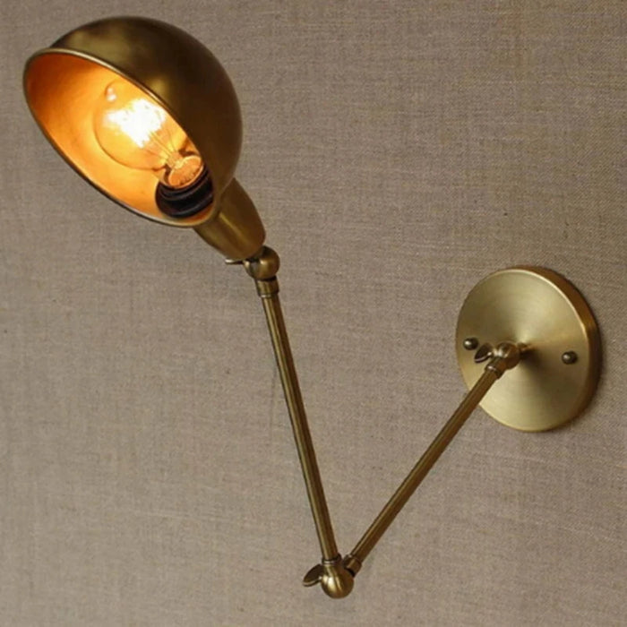 Vintage swing arm wall sconce with brass finish and industrial design, featuring an adjustable iron arm on a beige wall.