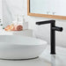 Modern tall black basin faucet with minimalist design next to a white sink in a stylish bathroom setting.