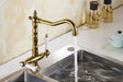 Antique bronze dual handle kitchen faucet mixer with water flowing, installed on a stainless steel sink.