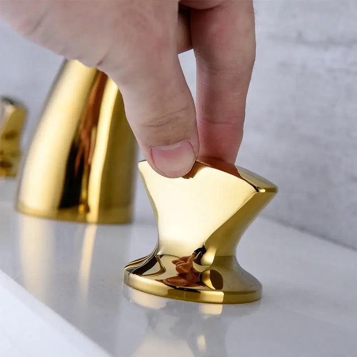 Hand adjusting brushed gold control knob of Roman tub filler set.