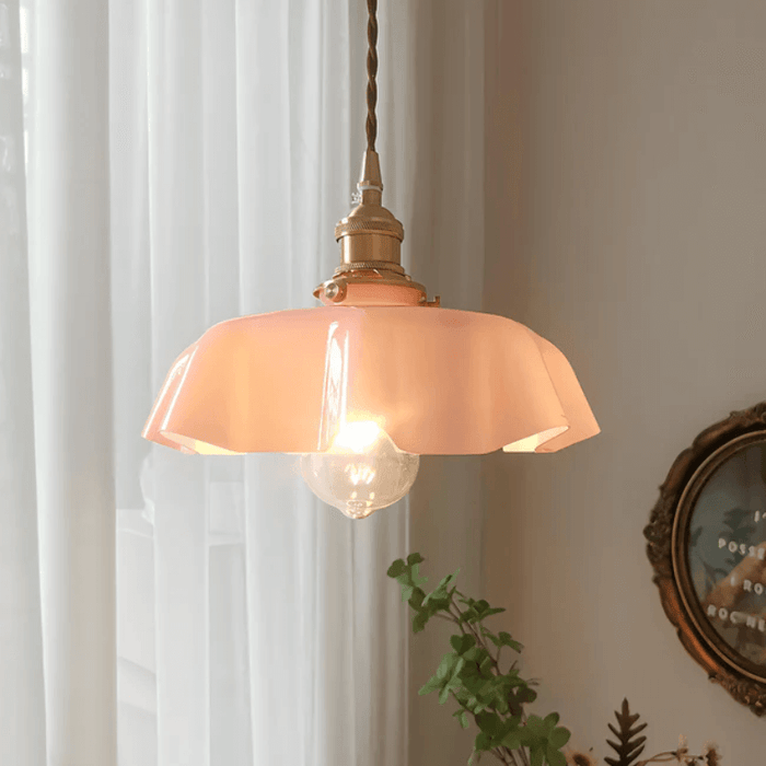 Retro French brass pendant light with scalloped pink glass shade hanging in a vintage-inspired room.