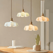 Retro French brass pendant lights with scalloped glass shades hanging over a wooden dining table.