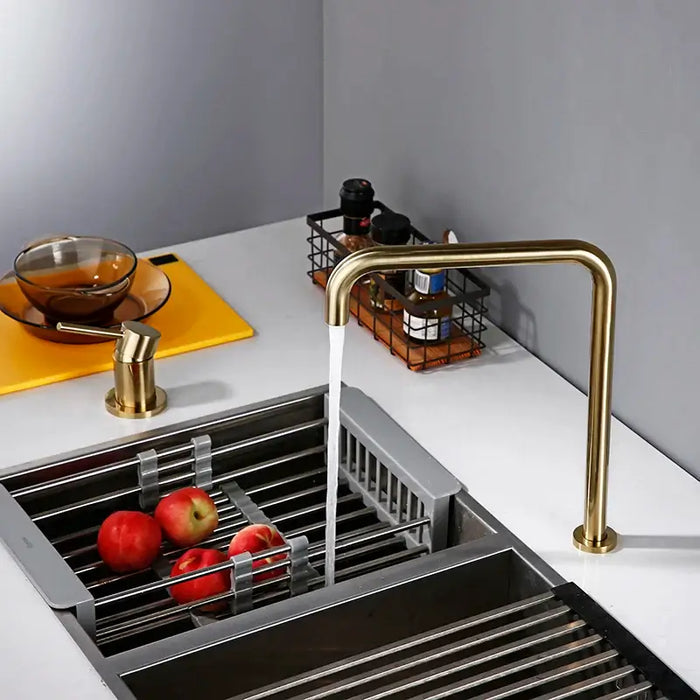 Elegant brass kitchen mixer tap with 360-degree swivel spout over sink, showcasing apples and modern countertop decor.