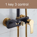 Black and gold shower mixer with 3 control system against a marble wall.