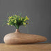 Modern stripe resin wood vase with intricate line patterns, featuring yellow and green floral arrangement on a wooden tabletop.