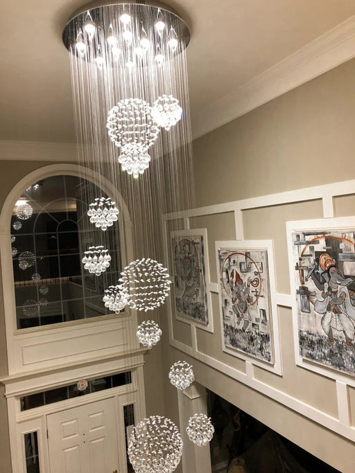 Luxury crystal sphere chandelier with stainless-steel finish illuminating a modern home interior.