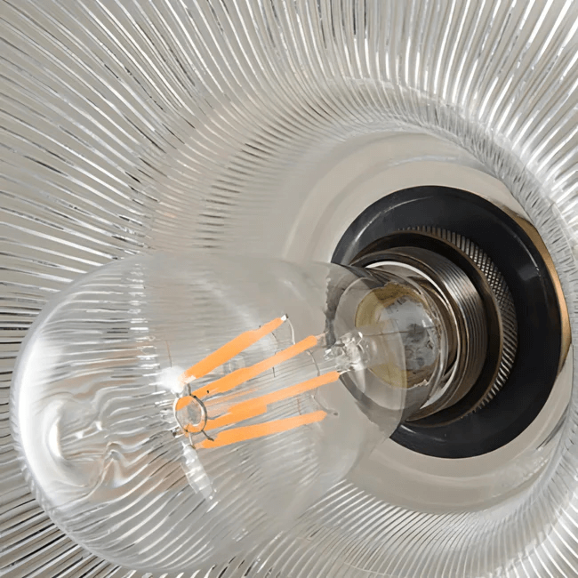 Close-up of vintage glass stripe pendant light with filament bulb and textured shade.