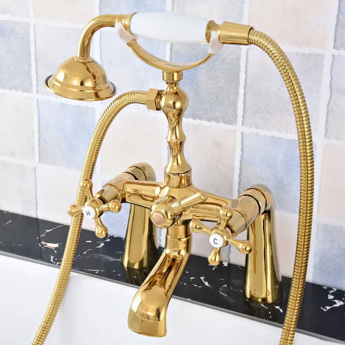 Luxury gold bathtub faucet with dual-control handles and hand shower, polished brass finish, mounted on a marble surface.