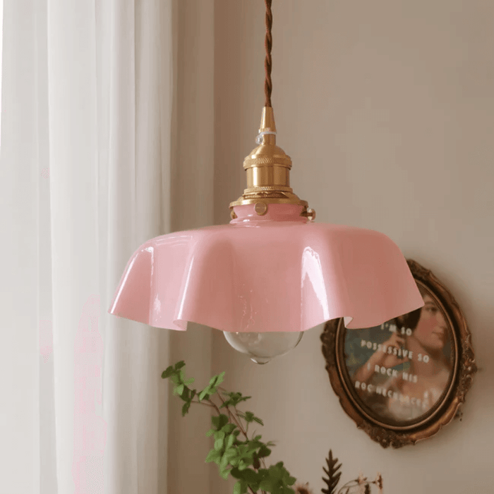 Retro French brass pendant light with scalloped pink shade hanging in a cozy room.