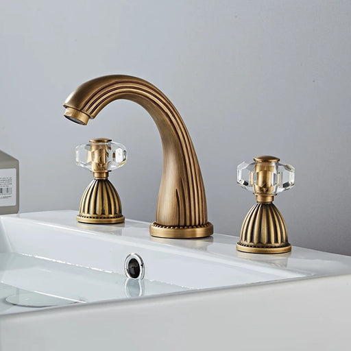 Elegant antique brass widespread basin mixer faucet with dual handles on white sink in modern bathroom.