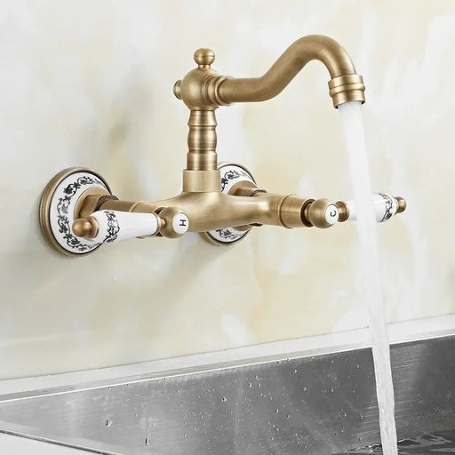 Antique brass faucet with dual handles, wall-mounted, featuring a swivel spout and dual-hole installation, flowing water into a sink.