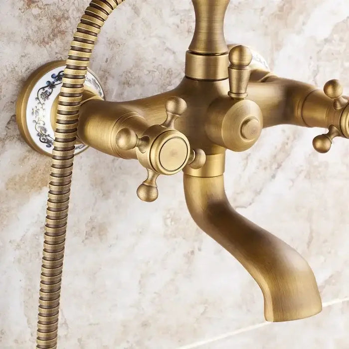 Antique brass handheld shower mixer with vintage design and porcelain accents on a bathroom wall.