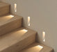 Frameless recessed LED wall lamps illuminating wooden staircase for subtle and elegant lighting.