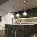 Modern kitchen setting with three hanging cage chandeliers illuminating a sleek black island.