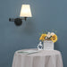 Folding swing arm wall lamp with LED fabric shade illuminating a table with sunflowers in a cozy room setting.