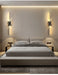 Modern minimalist vertical-horizontal LED wall sconce illuminating a stylish bedroom with a sleek bed and elegant decor.