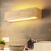 Elegant wood LED wall lamp with adjustable shade direction, mounted on a bathroom wall, providing warm and refined lighting.