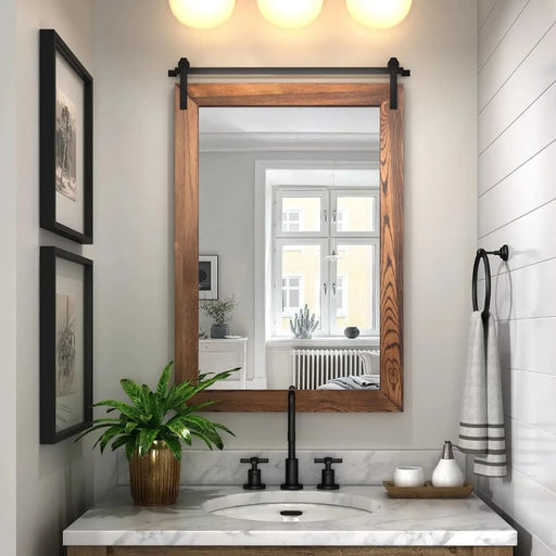 Rustic barn door mirror in a modern bathroom with a wood frame and black metal bracket, enhancing light and space with farmhouse style.