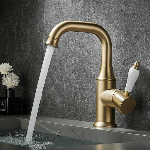 Brushed brass deck-mount basin faucet with flowing water, featuring a stylish single-handle design, enhancing bathroom elegance.