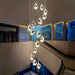 Luxury crystal dropping stones chandelier illuminating a modern interior staircase.