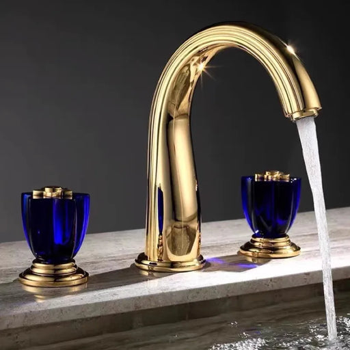 Luxury gold widespread basin faucet with dual handles in brass, featuring a sleek design and elegant water flow in a modern bathroom.