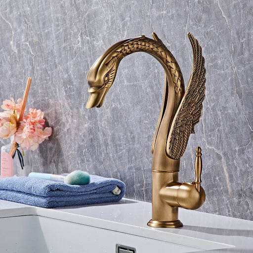 Elegant Luxury Swan Basin Mixer in gold finish installed in a modern bathroom setting with a marble wall background.