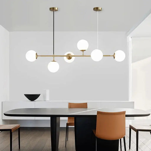 Modern glass ball pendant light hanging in a stylish dining room setting with sleek furniture.