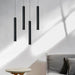 Modern black double-head LED pendant lights in a minimalist living room setting with soft natural lighting.