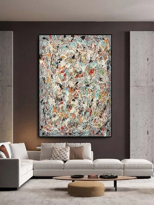 Pollock-style abstract canvas with colorful splatters on a vertical linen, displayed in a modern living room.