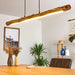 Rustic wooden LED pendant light illuminating a modern dining room with natural decor and plants.