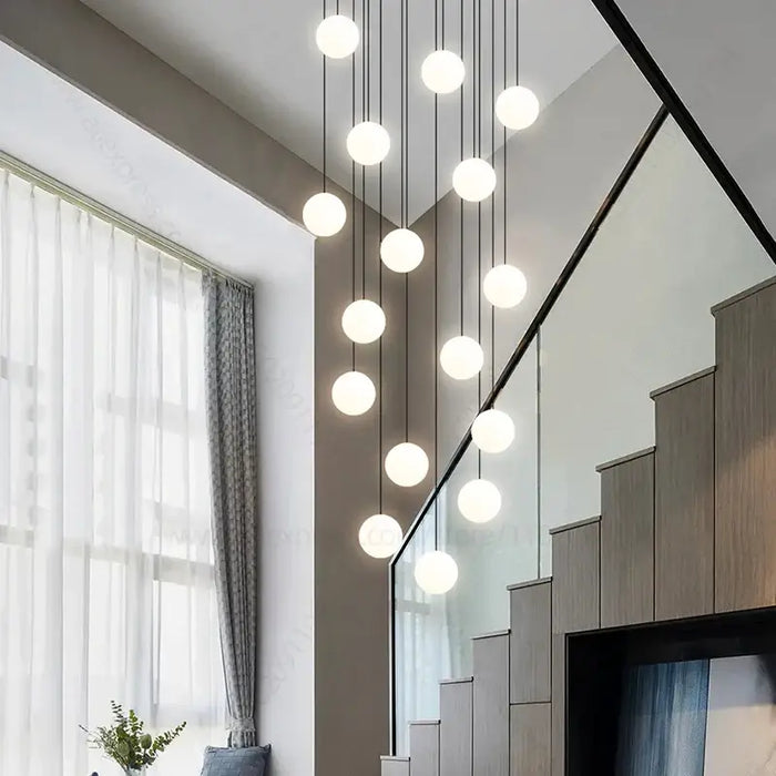 Minimalist multi-head LED chandelier with glowing spheres over a modern staircase, enhancing interior elegance and style.