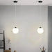 Modern round glass pendant lights hanging in a minimalist room with brass or black iron finish.