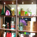 Decorative shelf display illuminated by LED downlights with various decor items including flowers, signs, and colorful boxes.