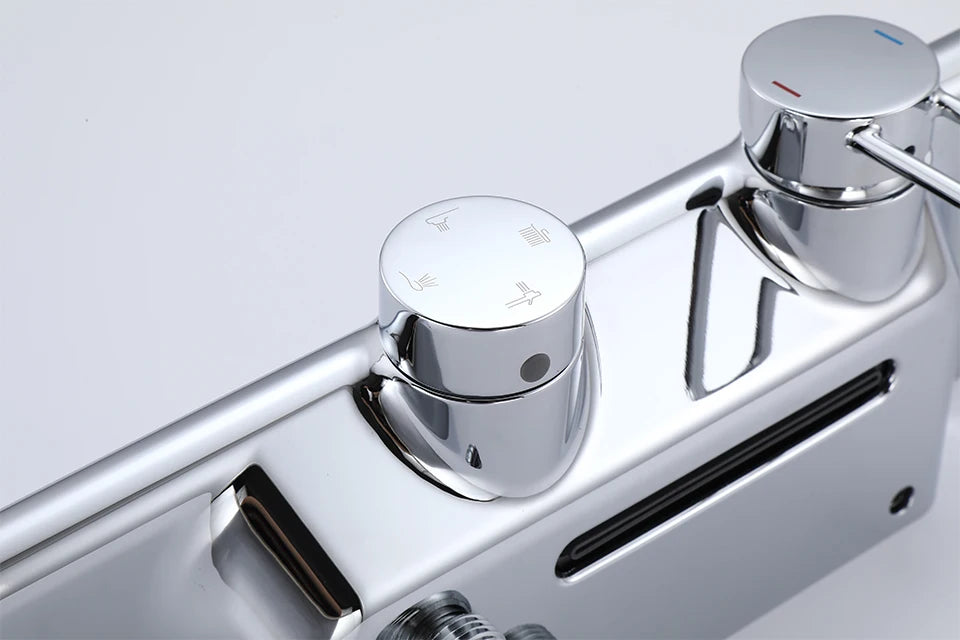 Close-up of chrome controls on luxury rainfall shower system set with separate knobs for water outlets.