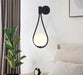 Nordic Elegance Drop Wall Lamp in black, featuring LED bulbs and frosted glass, mounted next to a bed with modern decor.