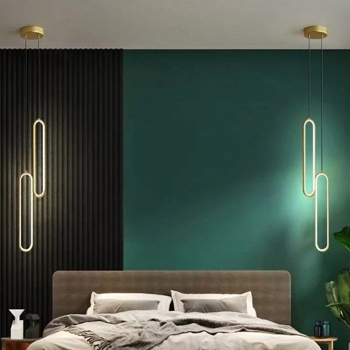 Modern black and gold LED pendant lights hanging in a stylish bedroom with green walls and a contemporary design.