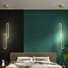 Modern black and gold LED pendant lights hanging in a stylish bedroom with green walls and a contemporary design.