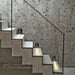 PIR sensor embedded step lights illuminate a modern concrete staircase with smart motion and light sensor technology.