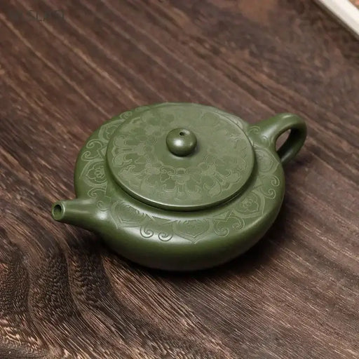 Handmade Green Yixing Clay Teapot with intricate design on wooden surface, ideal for an authentic Chinese tea experience.