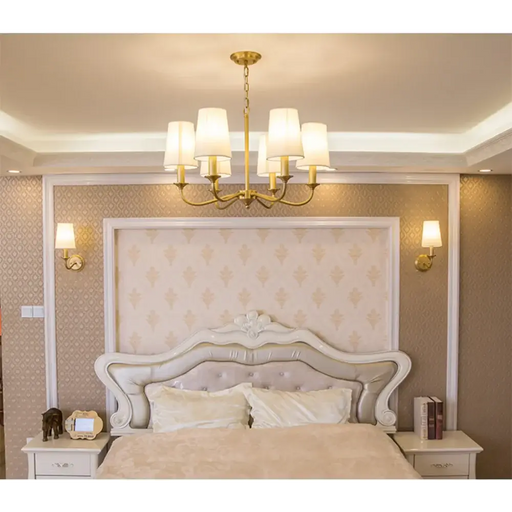 Elegant golden fabric pendant chandelier illuminating a luxurious bedroom setting.