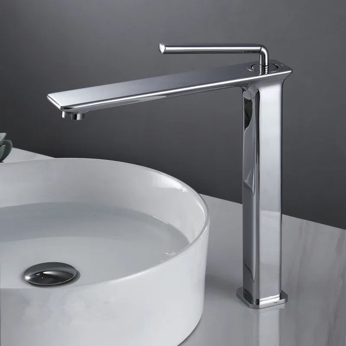 Modern brass basin faucet with single-handle design beside a white round sink, offering hot and cold water mixing.