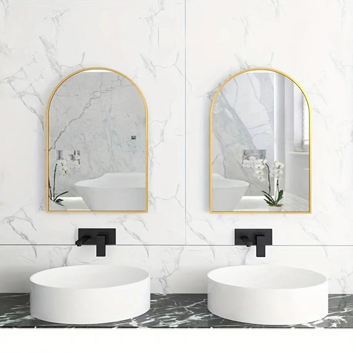 Large arch mirrors with gold frames in a modern bathroom setting above round white sinks.