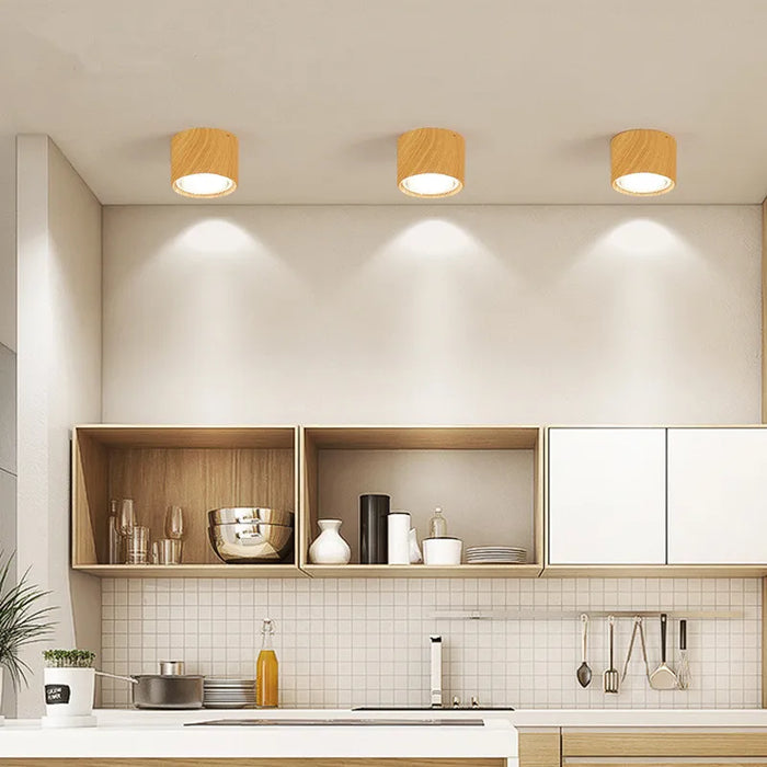 Modern kitchen with wood grain LED ceiling downlights illuminating sleek cabinets and countertops.