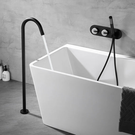 Sleek black floor-mounted bathtub faucet with modern design and curved spout next to a white freestanding bathtub in a contemporary bathroom.