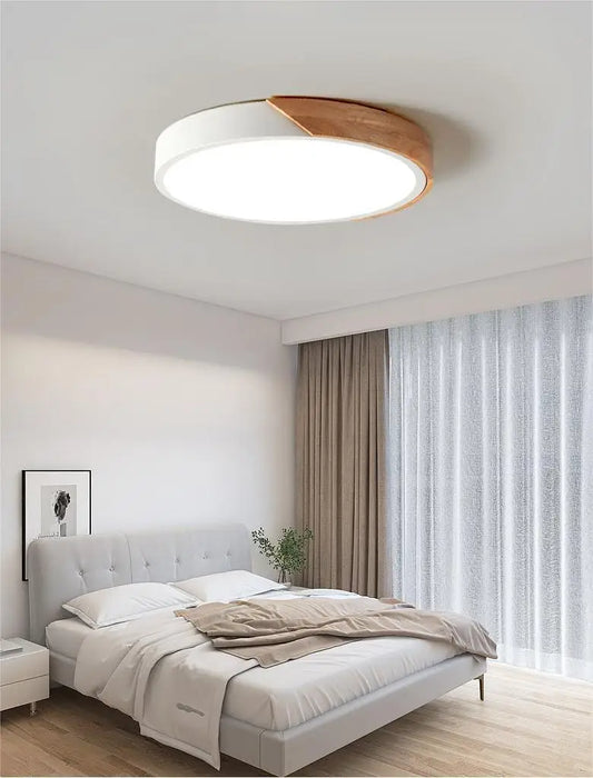 Modern round wooden LED ceiling light in a bedroom with neutral decor and natural light.